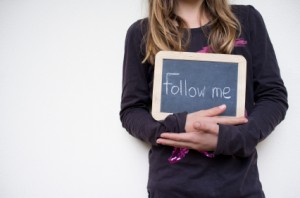 Frau hält Tafel mit Aufschrift "Follow me"